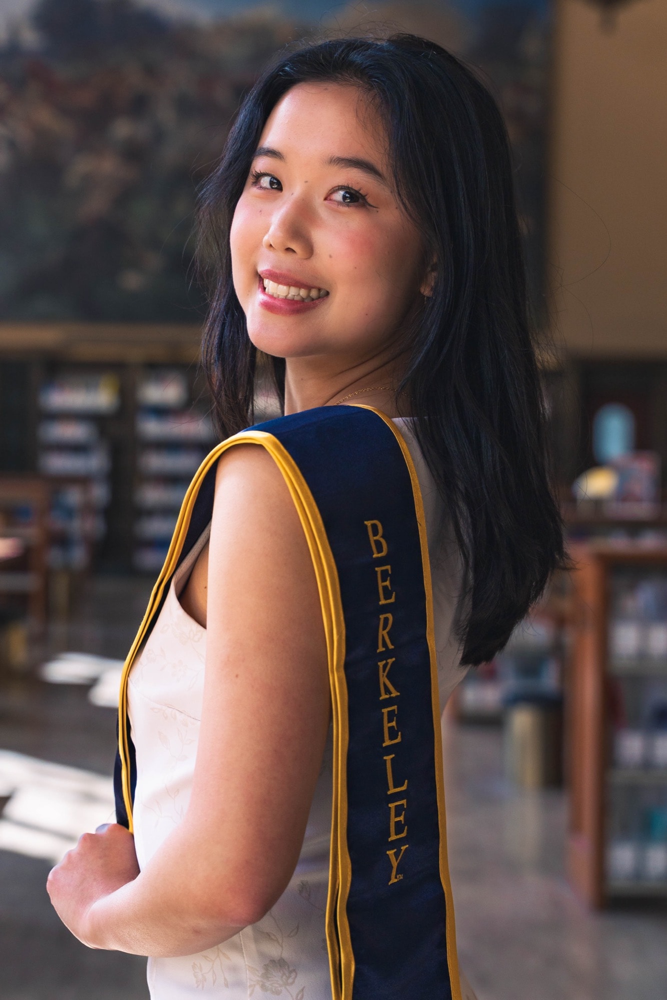 Graduate glancing over her shoulder in warm interior light
