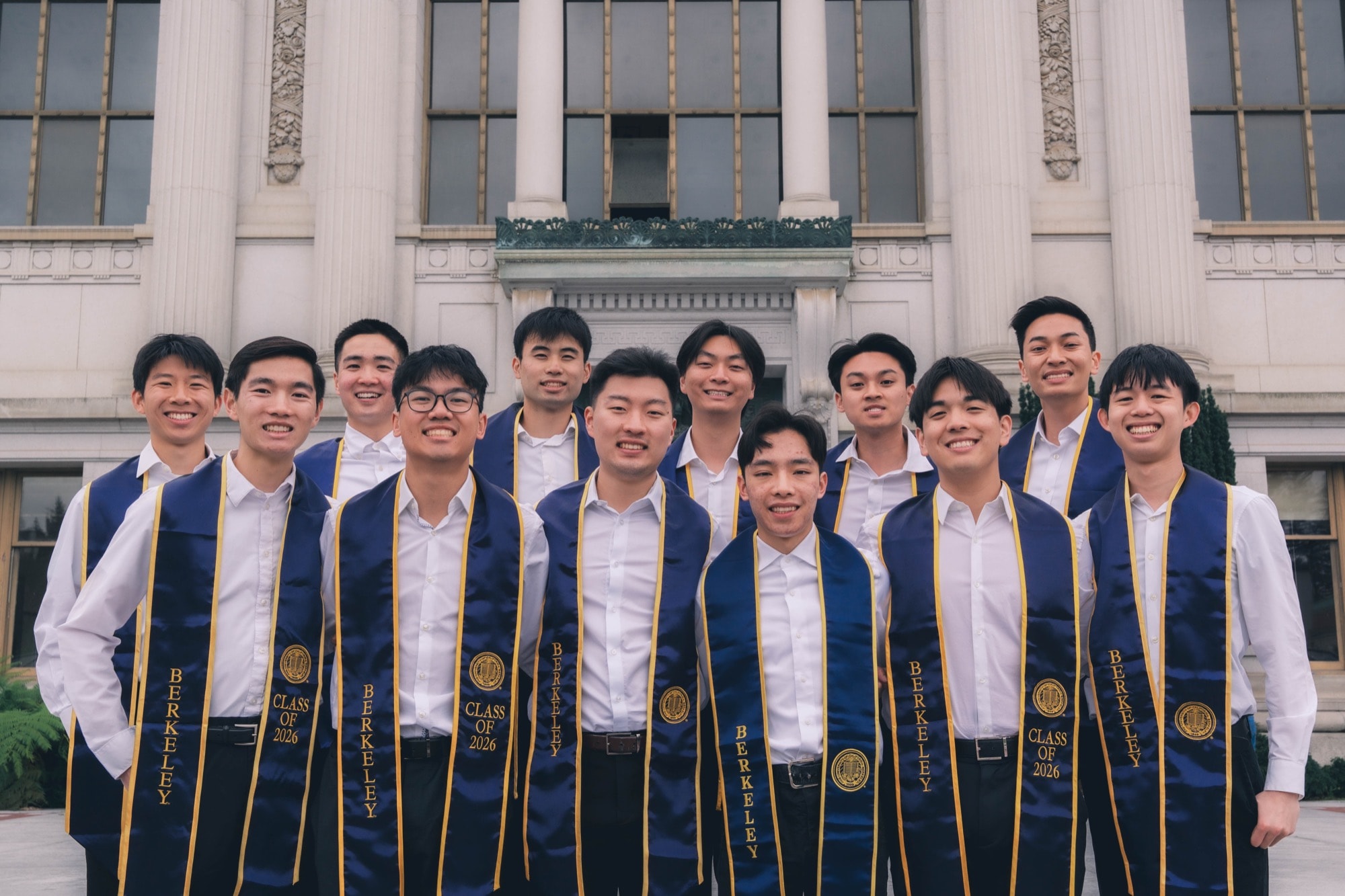 Graduates lined up on the steps of a campus building